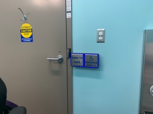 The buttons next to the washroom door - large square buttons. One say push to lock and the other is the standard automatic door open button