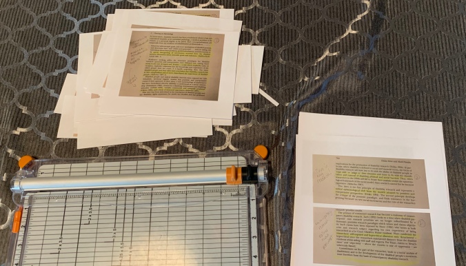 Pages printed with quotes, a paper cutter and some quotes cut down to size